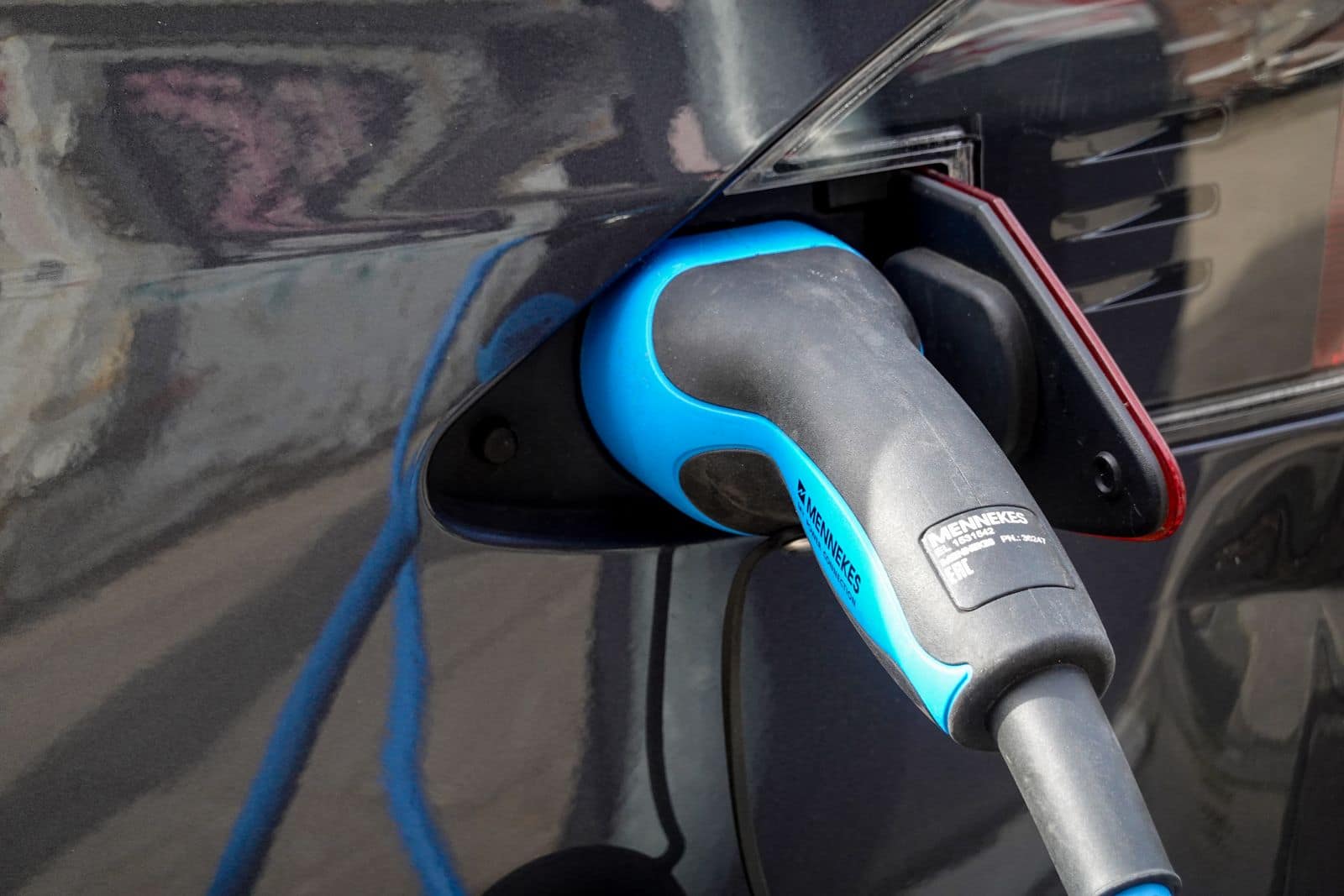 An electric vehicle charging connector plugged into a car's charge port