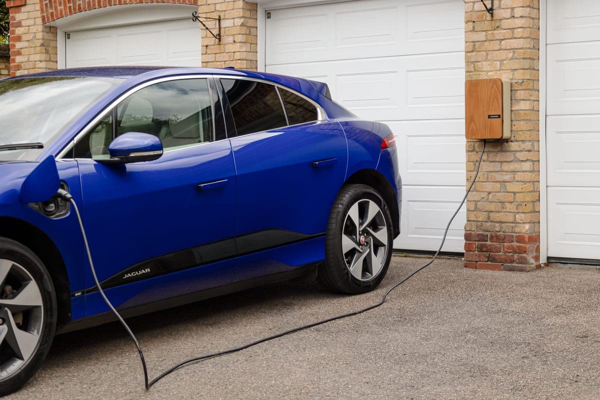 An electric car parked and plugged in to charge outside a modern home