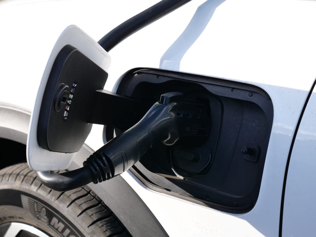 A close-up of an EV charging connector being held near a charge port