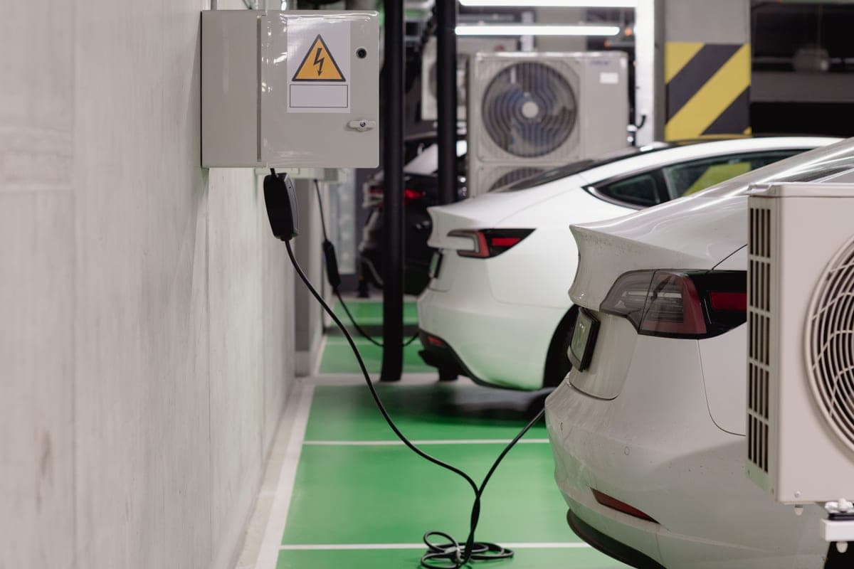An electric car charging from a wall-mounted Level 2 charger in a home garage