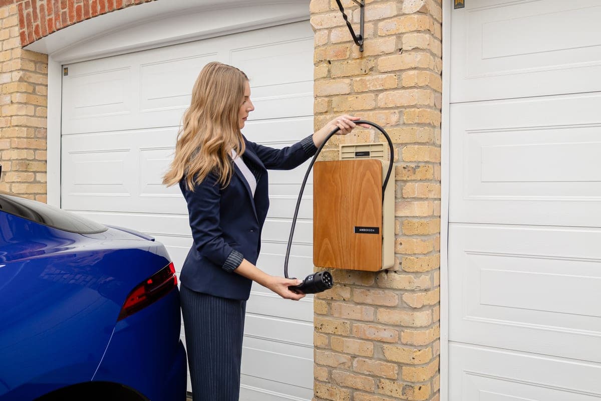 A Level 2 EV charging station mounted on a wall with its cable coiled